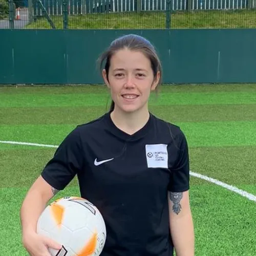 Emma Porteous, 30 under 30 nominee in 2023 holding a football in her hand smiling at the camera in a football field.
