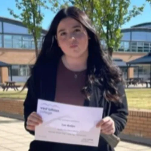 Zara Rankine, 30 under 30 nominee in 2023 holding a paper in her hand and smiling at the camera.