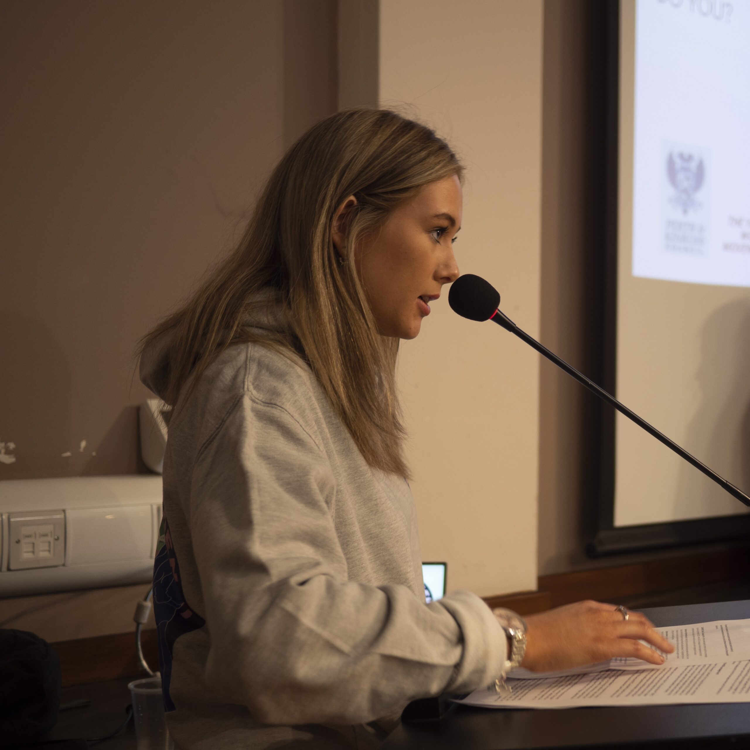 Young woman speaking into a microphone at a podium